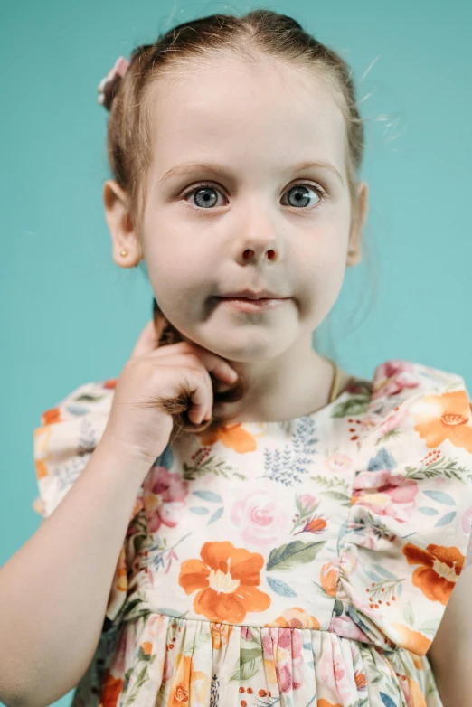 a little girl that is posing for a picture, a character portrait, inspired by Elsa Beskow, pexels, cyan photographic backdrop, wearing a cute top, cleft chin, floral
