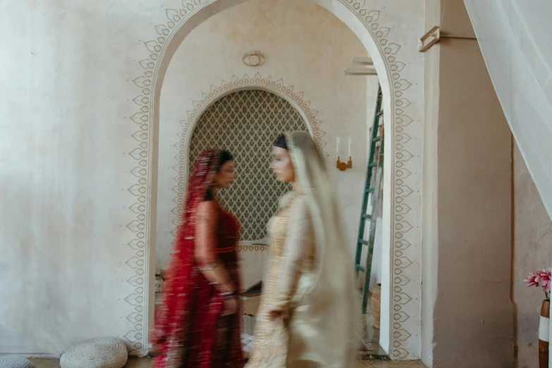 a couple of women standing next to each other, by Riad Beyrouti, pexels contest winner, hurufiyya, luxurious wedding, hindu aesthetic, background image, about to enter doorframe