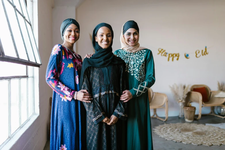 a group of three women standing next to each other, hurufiyya, happy expressions, official store photo, intricate clothing, riyahd cassiem