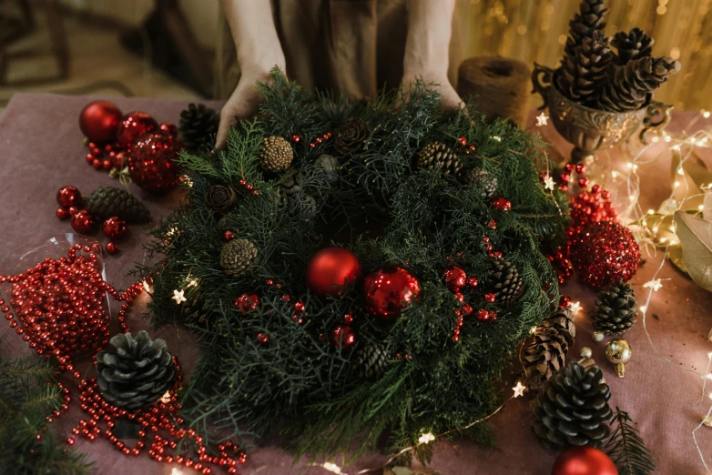 a close up of a christmas wreath on a table, a portrait, by Julia Pishtar, pexels, hurufiyya, hands holding big glowing orbs, crown of giant rubies, full-body view, seasonal