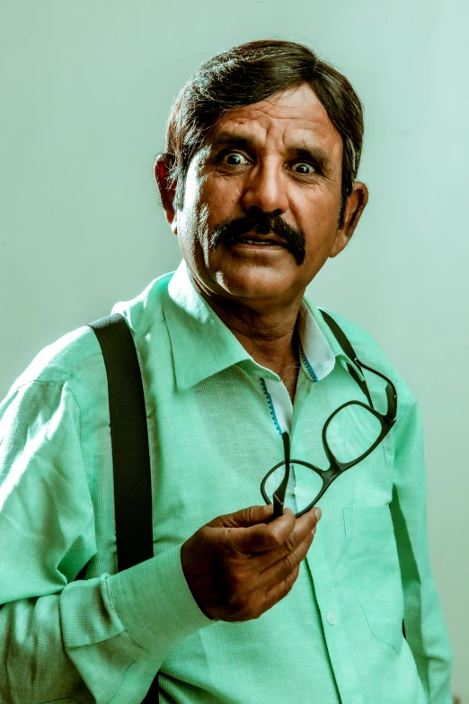 a man in a green shirt holding a pair of glasses, inspired by Narayan Shridhar Bendre, oldman with mustach, with a stethoscope, portrait mode, 2 5 6 x 2 5 6 pixels