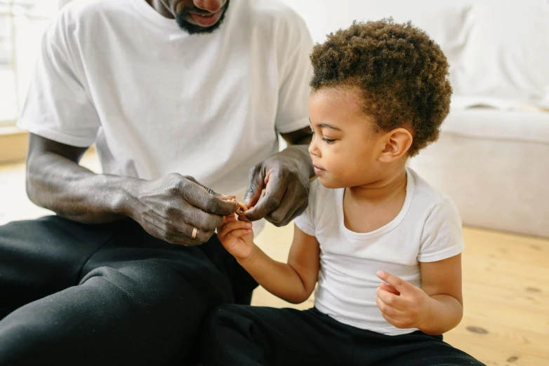 a man and a little girl sitting on the floor, pexels contest winner, with brown skin, sitting on man's fingertip, chocolate, toddler