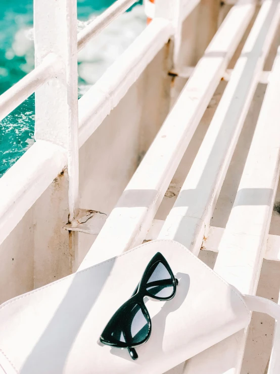 a pair of sunglasses sitting on top of a white bench, body of water, skincare, teal aesthetic, accurate image