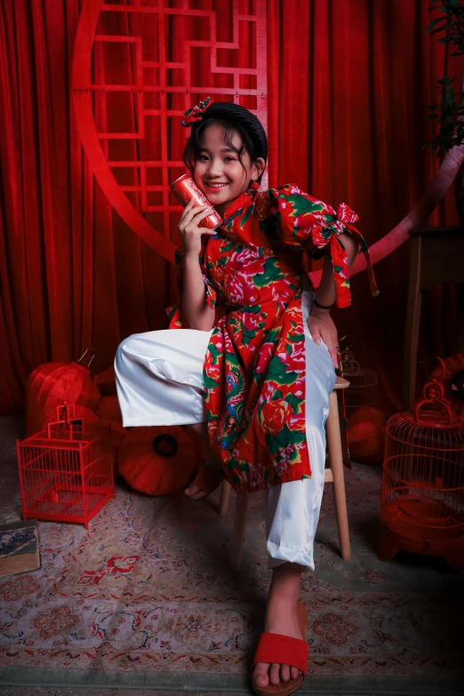 a woman sitting on a chair talking on a cell phone, a picture, inspired by Gao Kegong, pexels contest winner, wearing festive clothing, full body potrait holding bottle, red room, promotional image