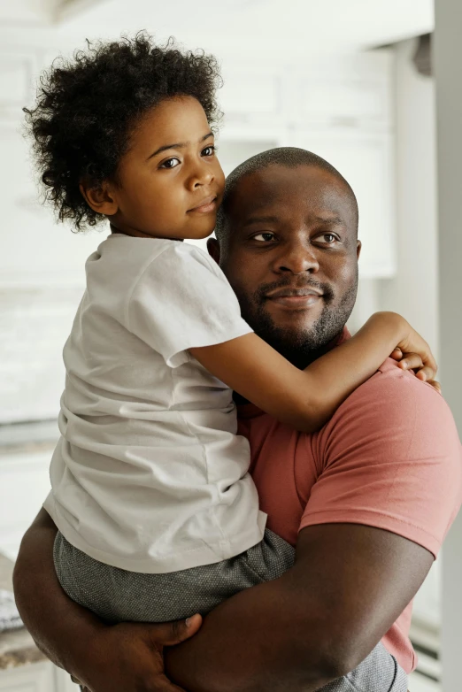 a man holding a small child in his arms, by Samuel Washington Weis, pexels contest winner, light skinned african young girl, hugging each other, handsome male, looking confident