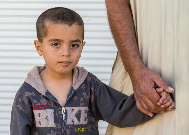 a close up of a person holding a child's hand, by Ibrahim Kodra, pexels contest winner, hurufiyya, iraq nadar, full body image, boy with neutral face, 15081959 21121991 01012000 4k