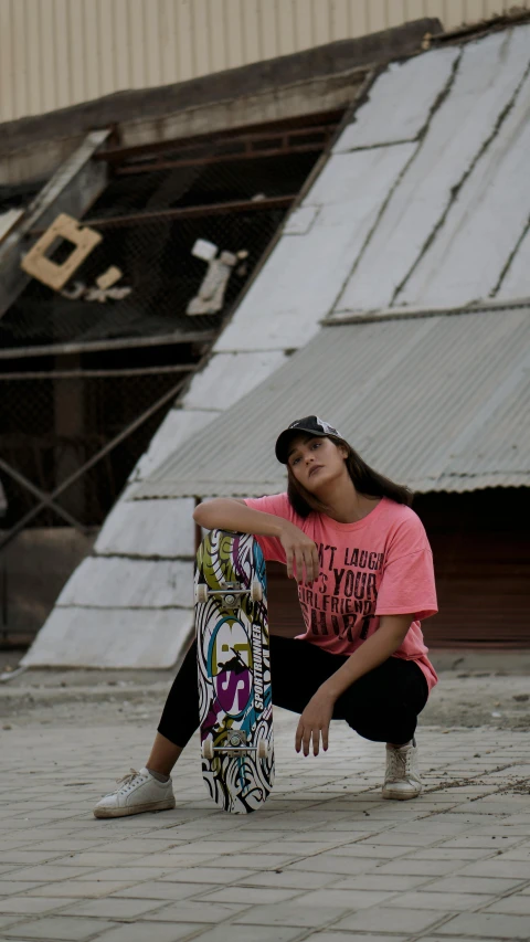 a woman kneeling on the ground with a skateboard, by Basuki Abdullah, pink shirt, official store photo, bella poarch, wearing a tee shirt and combats