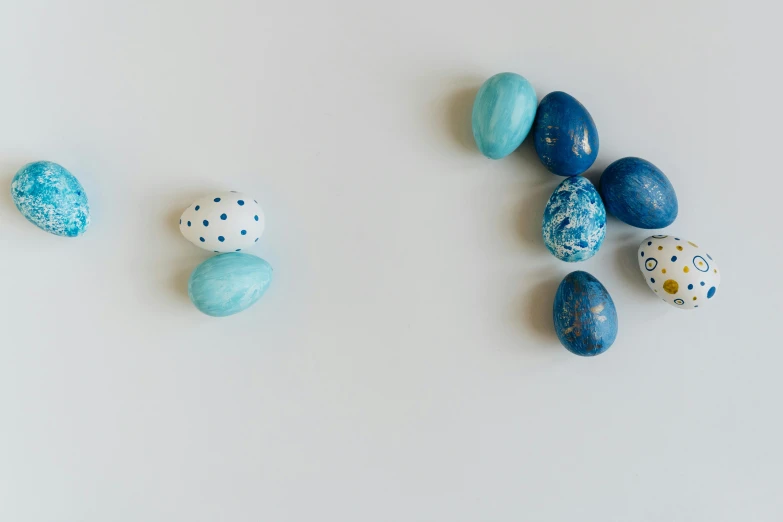 a white table topped with lots of blue and white eggs, trending on unsplash, visual art, background image, gravels around, floating objects, with a white background