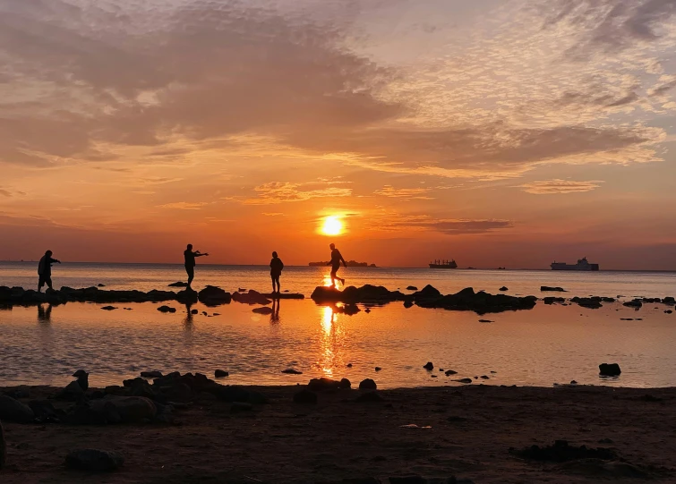 a group of people standing on top of a sandy beach, during a sunset, sup, stepping stones, fishing