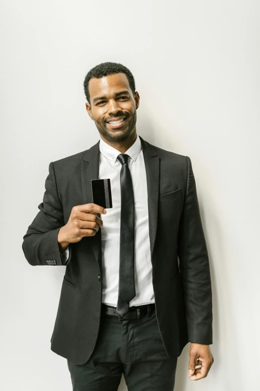 a man in a suit and tie holding a cell phone, holding a drink, black main color, black man, business card