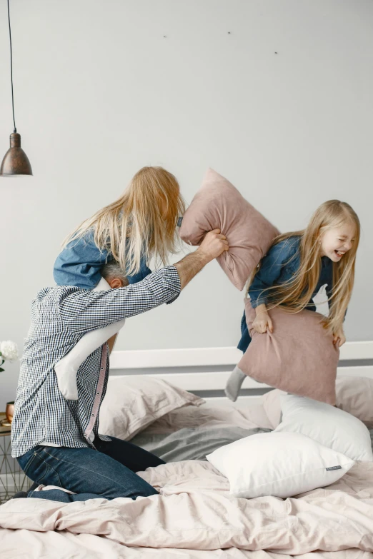 two little girls playing with pillows on a bed, by Adam Marczyński, pexels contest winner, father with child, punching, plain background, gif