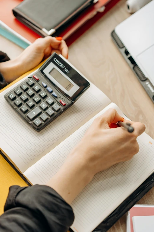 a woman sitting at a desk using a calculator, a cartoon, trending on pexels, sustainable materials, low quality photo, thumbnail, round format