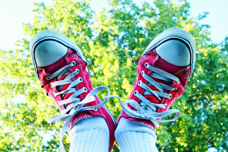 a pair of red sneakers sitting on top of a skateboard, by Jan Rustem, mid view from below her feet, springtime vibrancy, converse, standing on 2 feet