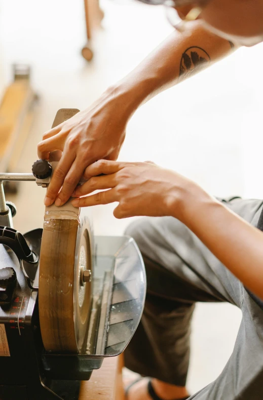 a close up of a person working on a machine, trending on pexels, arts and crafts movement, brown, wheels, hand holding a knife, a wooden