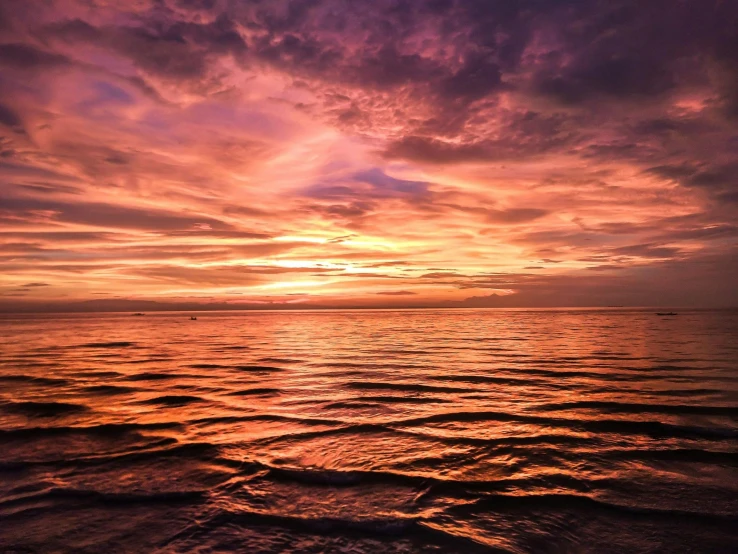 a large body of water under a cloudy sky, by Robbie Trevino, pexels contest winner, romanticism, orange and red sky, heat ripples, endless sea, pink