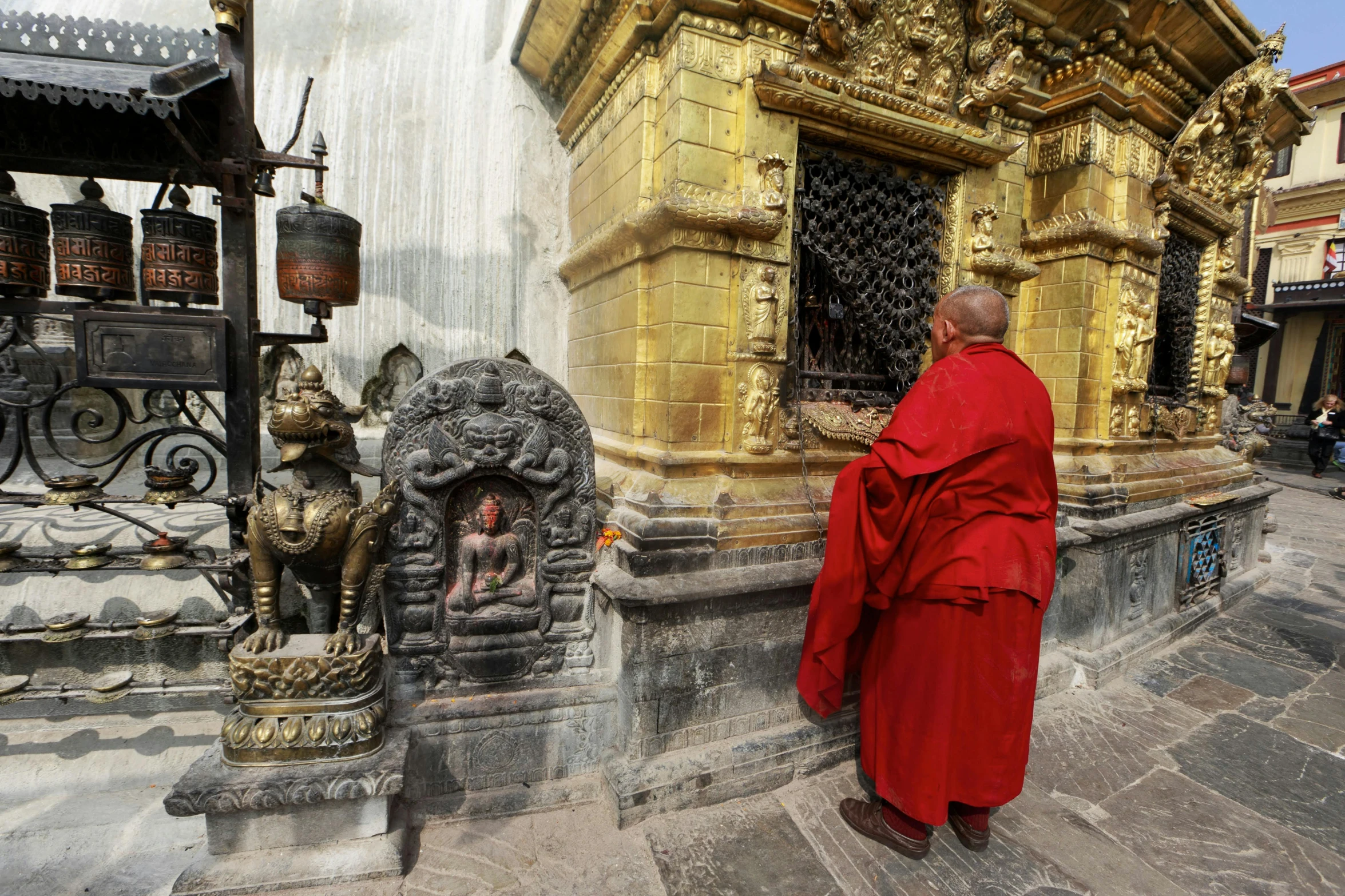 a man in a red robe standing in front of a building, inside her temple, gold and red metal, man sitting facing away, nepal