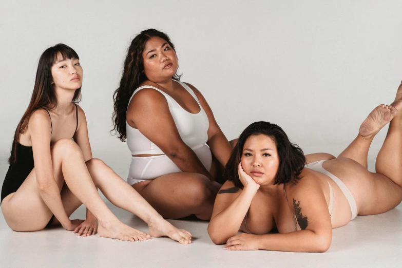 a group of women sitting on top of a white floor, curvy body, half asian, as 3 figures, burly