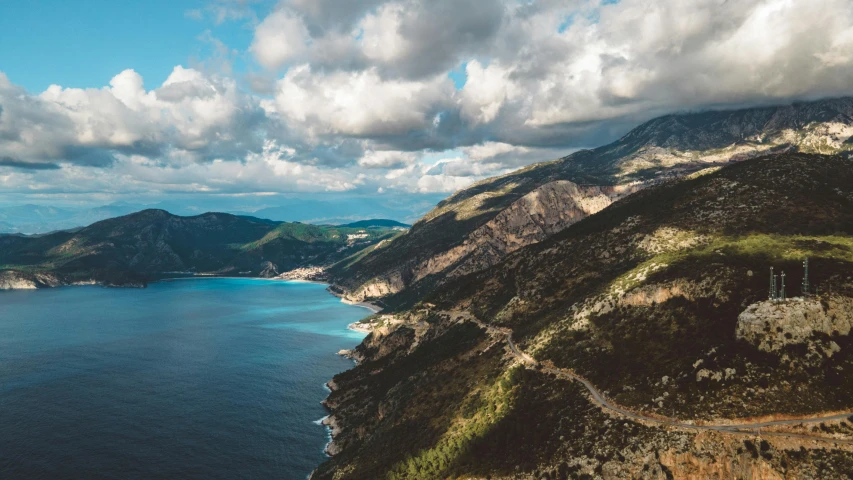 a large body of water next to a lush green hillside, by Emma Andijewska, pexels contest winner, realism, road to the sea, mount olympus, high quality product image”, conde nast traveler photo