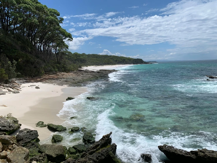 a large body of water next to a sandy beach, a photo, plein air, tamborine, beach on the outer rim, white beaches, high cliff