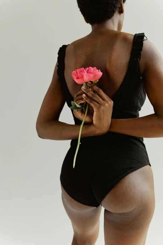 a woman in a black bodysuit holding a pink flower, unsplash, renaissance, ebony skin, wearing black shorts, natural point rose', wearing nothing