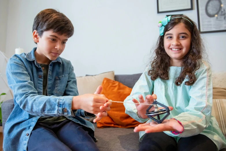 a couple of kids sitting on top of a couch, kinetic art, super conducters, sitting with wrists together, avatar image, cardistry