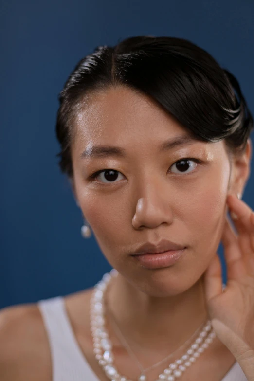 a woman in a white tank top holding a cell phone to her ear, an album cover, inspired by Kim Tschang Yeul, unsplash, hyperrealism, close - up face portrait, symetrical japanese pearl, with a blue background, flawless epidermis