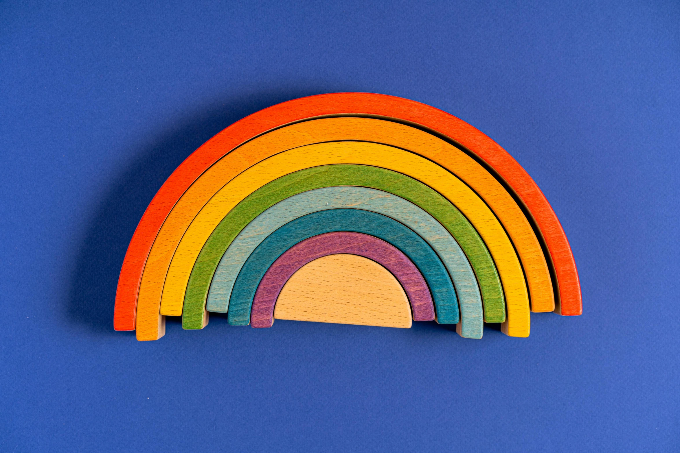 a wooden rainbow on a blue background, bauhaus, multiplayer set-piece, sun set, different sizes, group of seven