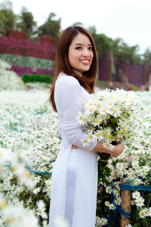 a woman in a white dress holding a bunch of flowers, inspired by Cui Bai, happening, flower fields, ao dai, with an elegant smile, wearing white skirt