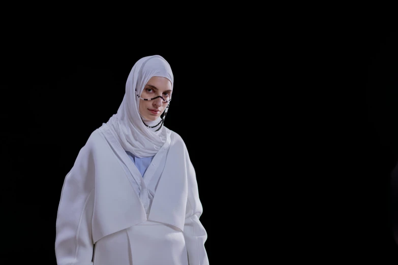 a woman standing in front of a black background, inspired by Anna Füssli, hurufiyya, wearing white clothes, vetements, ameera al taweel, slide show