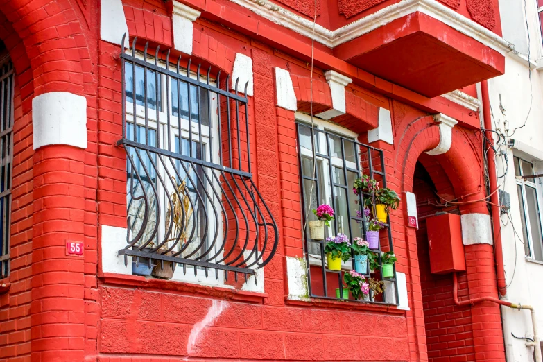 a fire hydrant sitting in front of a red building, by Julia Pishtar, pexels contest winner, art nouveau, wires hanging across windows, window with flower box, neo - andean architecture, in a row