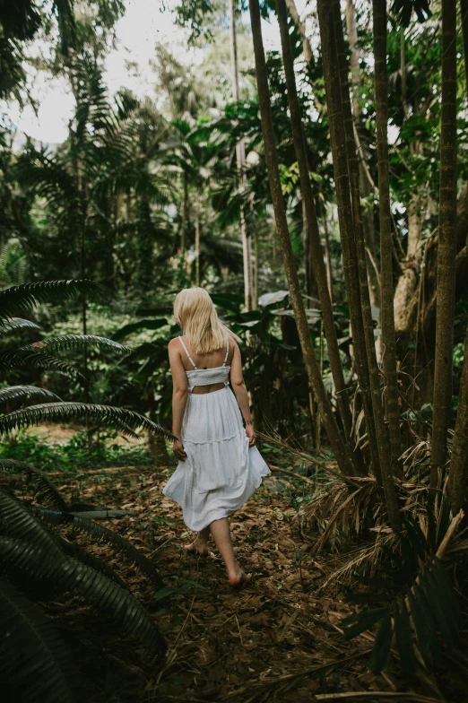 a woman in a white dress walking through a forest, by Jessie Algie, unsplash contest winner, tropical style, ( ( ( kauai ) ) ), blonde, lush greens