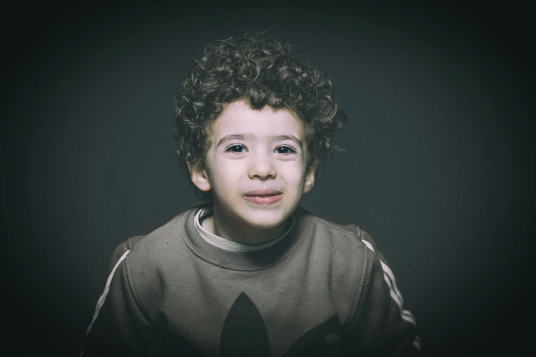 a young boy with curly hair posing for a picture, pexels contest winner, hyperrealism, dark grey backdrop studio, medium format. soft light, atef, ((portrait))