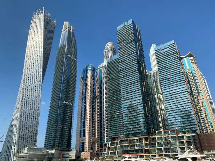 a group of tall buildings next to a body of water, hurufiyya, in style of norman foster, photograph taken in 2 0 2 0, dubai, low-angle