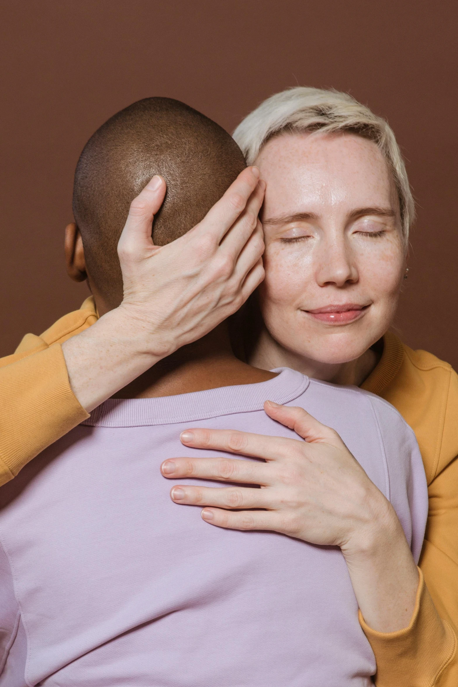 a woman hugging a man with her eyes closed, trending on pexels, renaissance, non-binary, plain background, compassion, blond