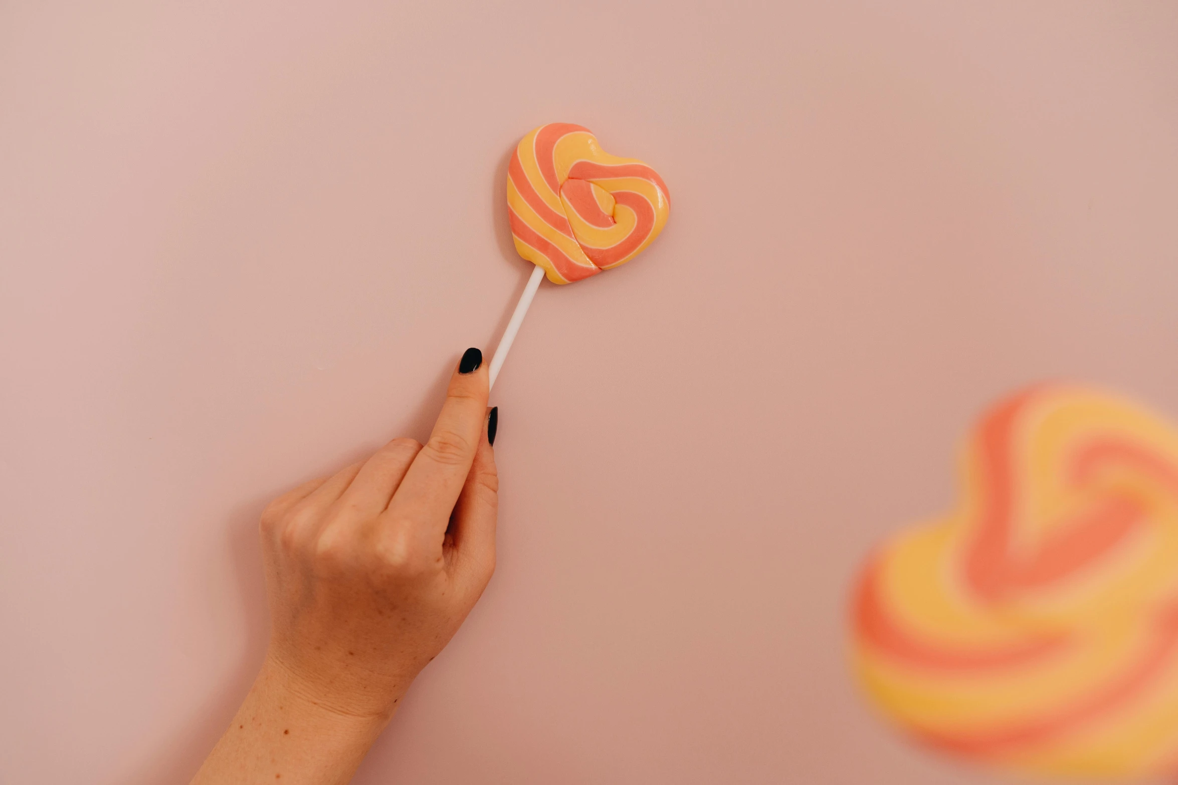 a close up of a person holding a lollipop, inspired by Ödön Márffy, trending on pexels, pink and orange, swirly, instagram post, empty background