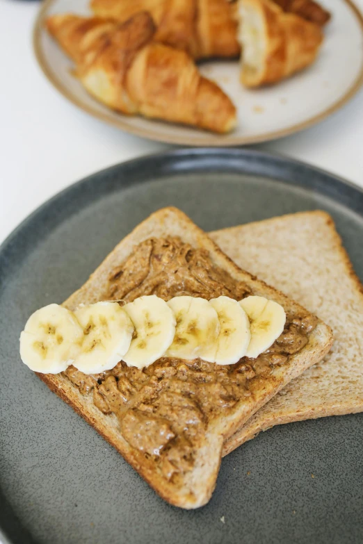 a plate topped with peanut butter and banana slices, by Nina Hamnett, unsplash, brown bread with sliced salo, sloppy, artoast8p, grey