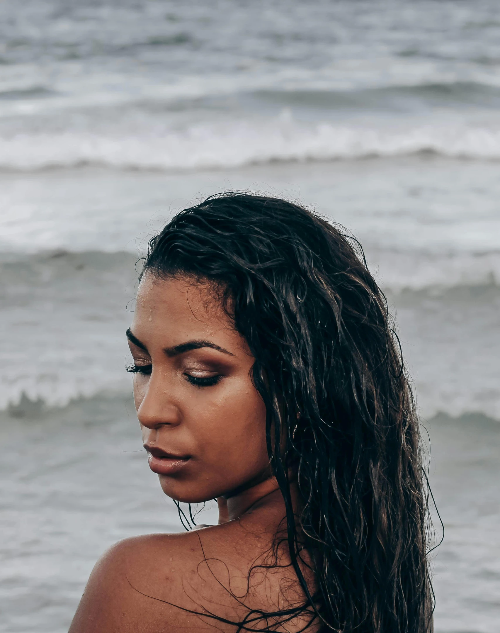 a woman standing on top of a beach next to the ocean, an album cover, inspired by Elsa Bleda, trending on unsplash, renaissance, she has olive brown skin, wet look, woman with freckles, portrait of vanessa morgan