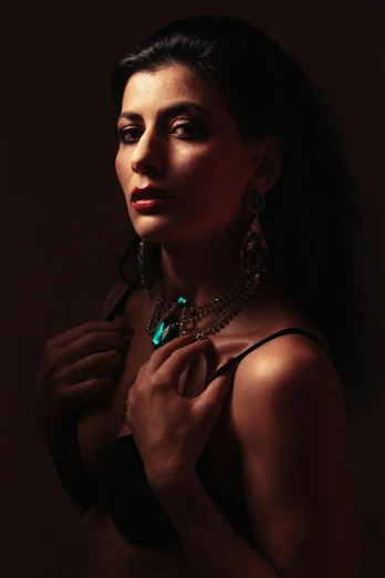 a woman posing for a picture in a dark room, a colorized photo, inspired by Elsa Bleda, pexels contest winner, covered in jewels, middle eastern skin, high key lighting, candid!! dark background