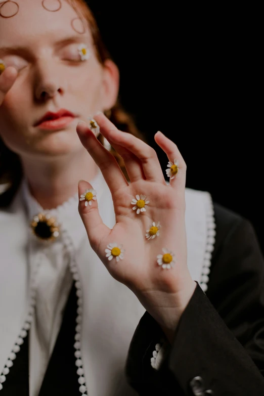 a woman with her hands on her face, an album cover, inspired by Elsa Bleda, trending on pexels, aestheticism, holding daisy, baroque art jewelry, corrected hands, miniature cosmos