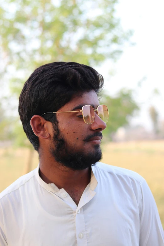 a man with glasses standing in a field, a picture, pexels contest winner, samikshavad, profile image, around 1 9 years old, headshot profile picture, slight yellow hue