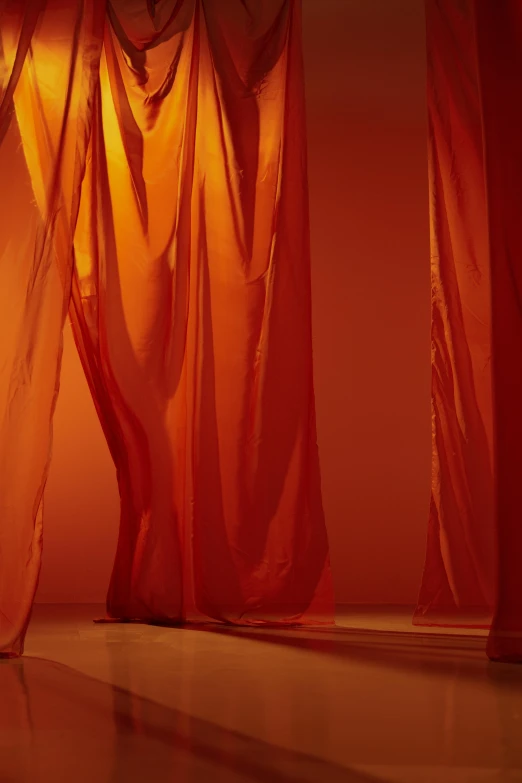 a woman standing in front of a red curtain, inspired by Christo, unsplash, gutai group, orange light, showstudio, made of fabric, close - up studio photo