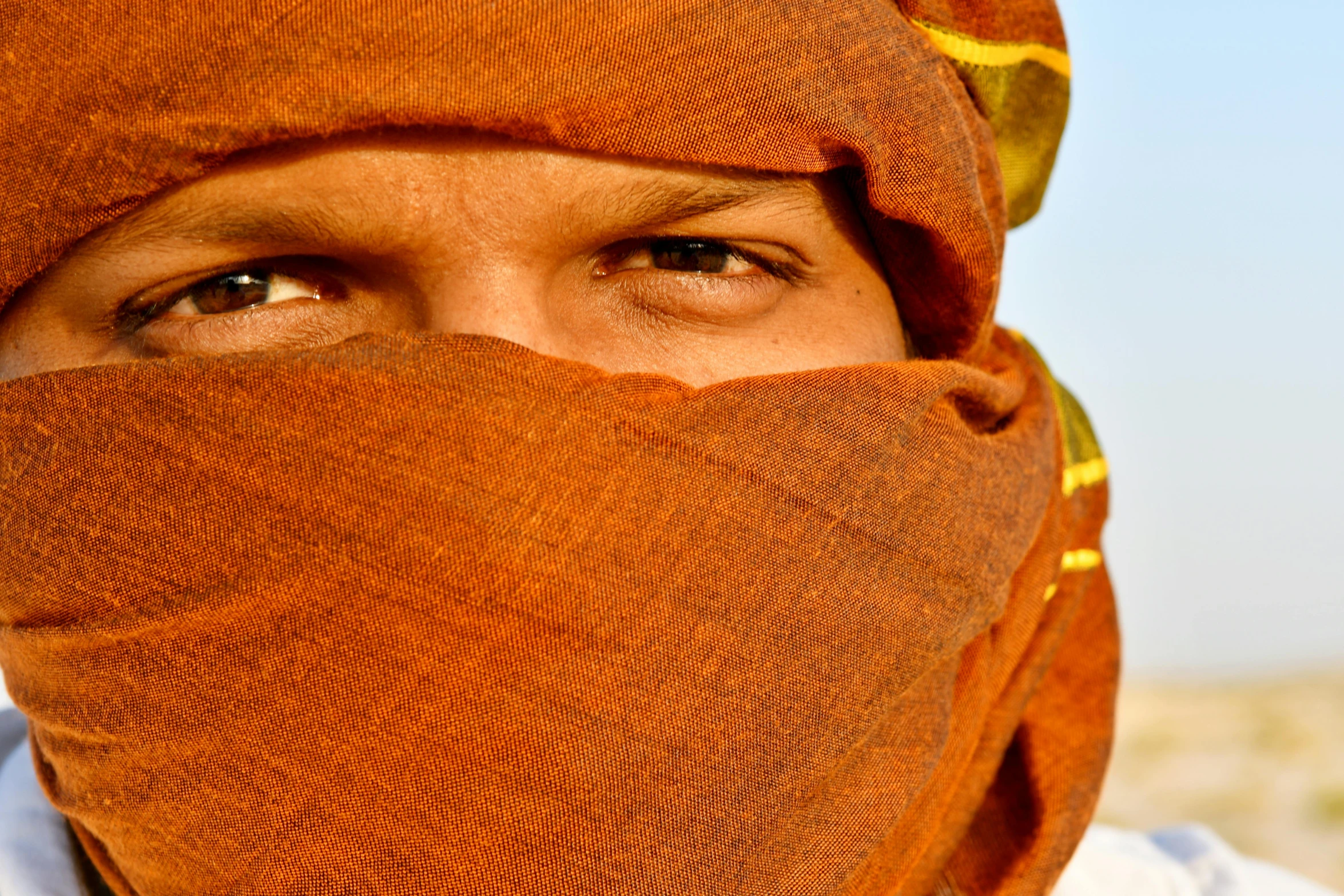 a close up of a person wearing a scarf, by Thomas Häfner, pexels contest winner, renaissance, desert breathing armor, orange balaclava, indian, confident shaded eyes