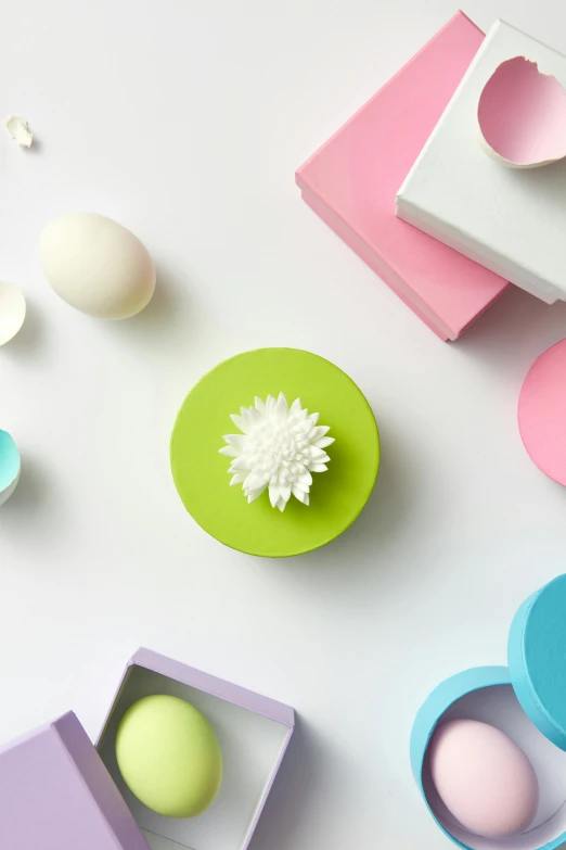 a white table topped with colorful boxes and eggs, depicting a flower, product image, pastel green, chrysanthemum eos-1d