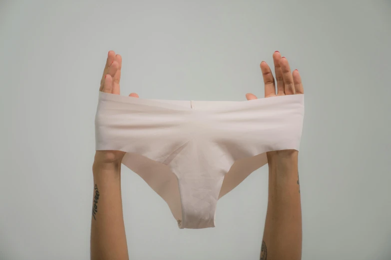 a person holding up a pair of underwear, unsplash, light blush, full front view, seamless, unsanitary