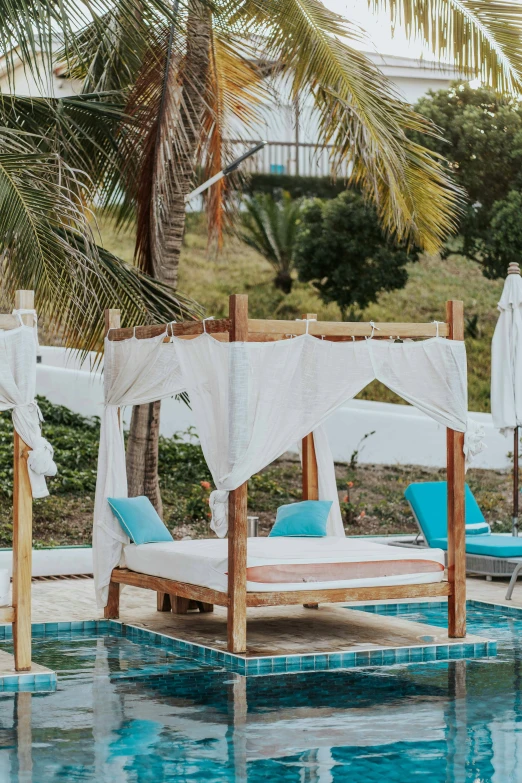 a couple of beds sitting in the middle of a pool, canopy, white and teal garment, madagascar, seaview