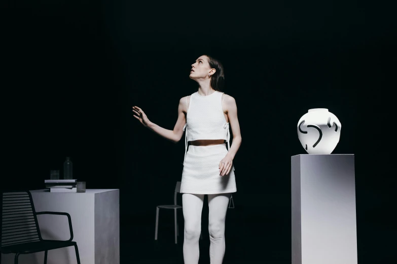 a woman standing in front of a white sculpture, an album cover, inspired by Anna Füssli, conceptual art, emma watson sitting in chair, in a space station, hermes ad, vessels