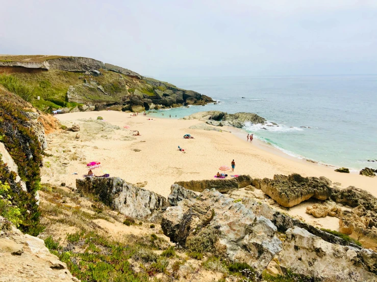 a group of people standing on top of a sandy beach, les nabis, an ocean, flatlay, rocky cliff, arrendajo in avila pinewood