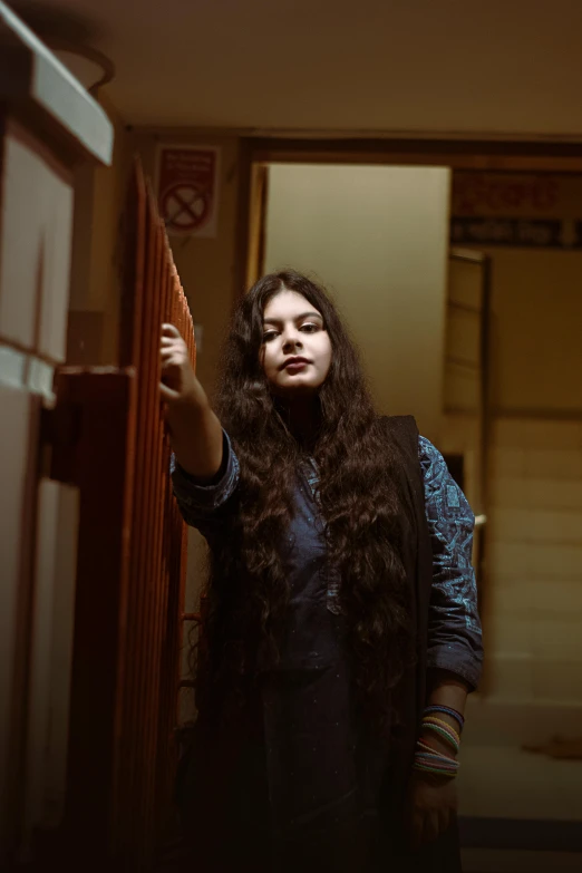 a woman standing next to a refrigerator in a kitchen, an album cover, inspired by Elsa Bleda, pexels contest winner, long wavy dark hair, in an elevator, ( ( theatrical ) ), hippie