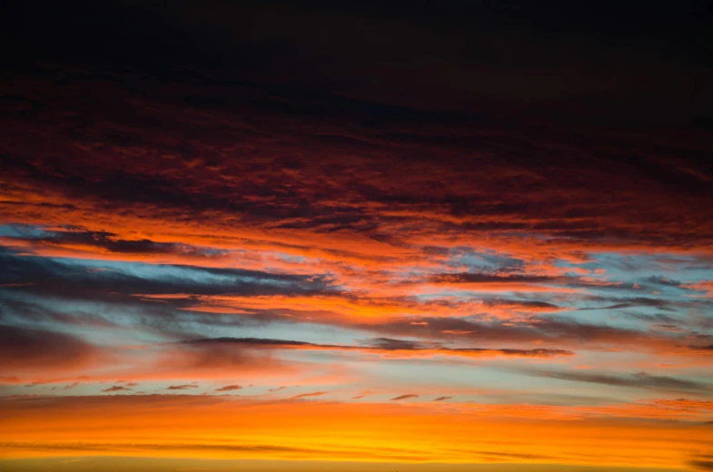 a large body of water with a sunset in the background, a picture, inspired by Frederic Church, unsplash, dark oranges reds and yellows, layered stratocumulus clouds, beautiful new mexico sunset, color ( sony a 7 r iv