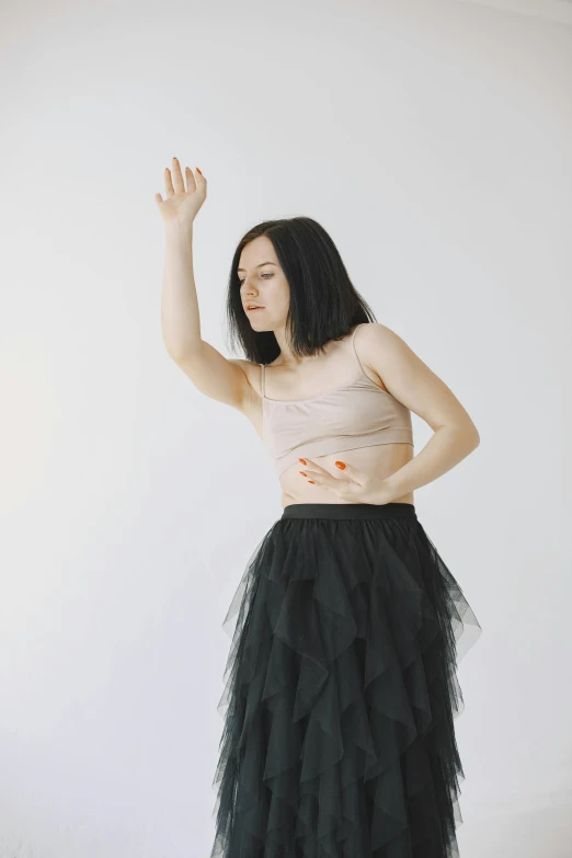 a woman standing in front of a white wall, an album cover, by Attila Meszlenyi, unsplash, renaissance, goth people dancing, crying and reaching with her arm, ballerina, long thin black hair